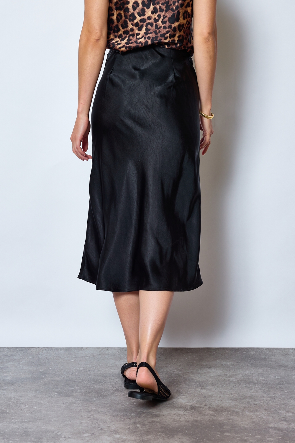 Réf. 41051 - Jupe longueur midi à la coupe évasée. Taille plate sans ceinture apparente pour un fini épuré. Matière satinée offrant un tombé souple et élégant. Fermeture discrète sur le côté.