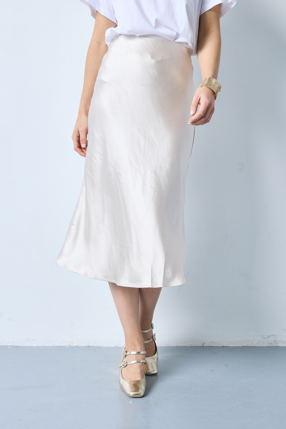 Réf. 41051A - Jupe longueur midi à la coupe évasée. Taille plate sans ceinture apparente pour un fini épuré. Matière satinée offrant un tombé souple et élégant. Fermeture discrète sur le côté.