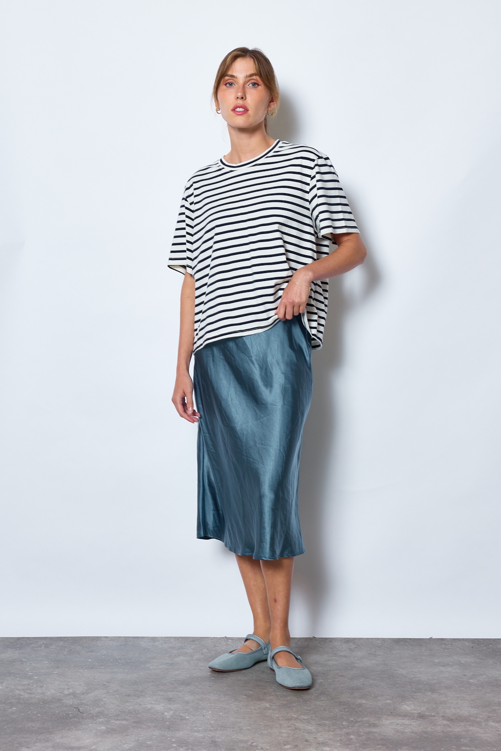 Réf. 41051B - Jupe longueur midi à la coupe évasée. Taille plate sans ceinture apparente pour un fini épuré. Matière satinée offrant un tombé souple et élégant. Fermeture discrète sur le côté.