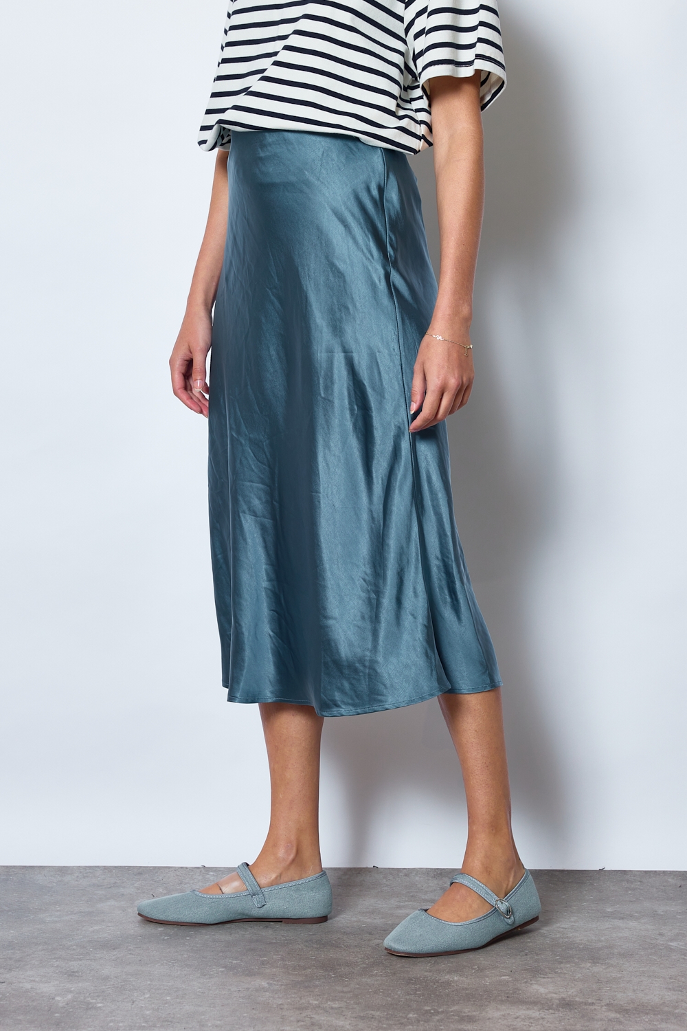 Réf. 41051B - Jupe longueur midi à la coupe évasée. Taille plate sans ceinture apparente pour un fini épuré. Matière satinée offrant un tombé souple et élégant. Fermeture discrète sur le côté.
