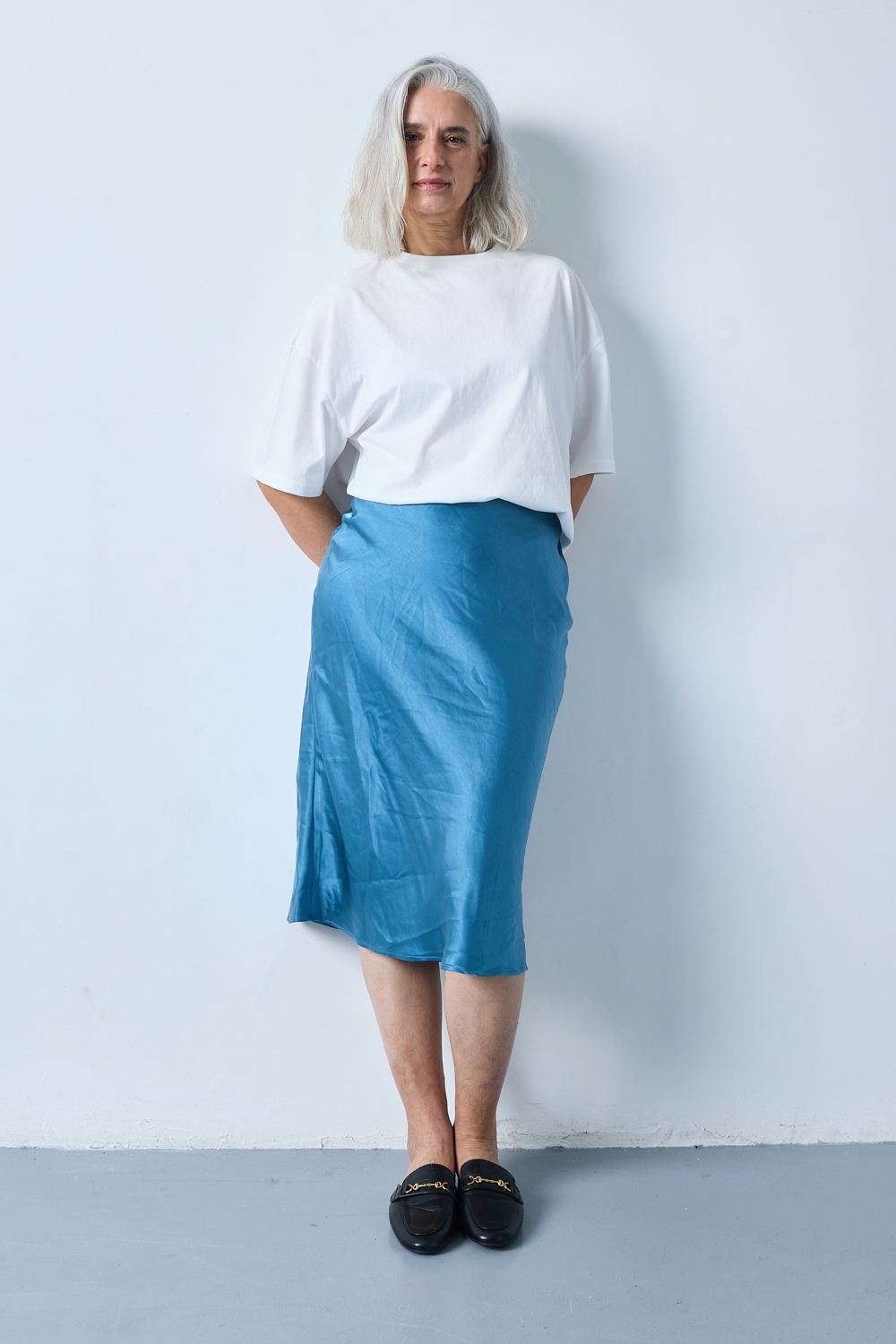 Réf. 41051B - Jupe longueur midi à la coupe évasée. Taille plate sans ceinture apparente pour un fini épuré. Matière satinée offrant un tombé souple et élégant. Fermeture discrète sur le côté.