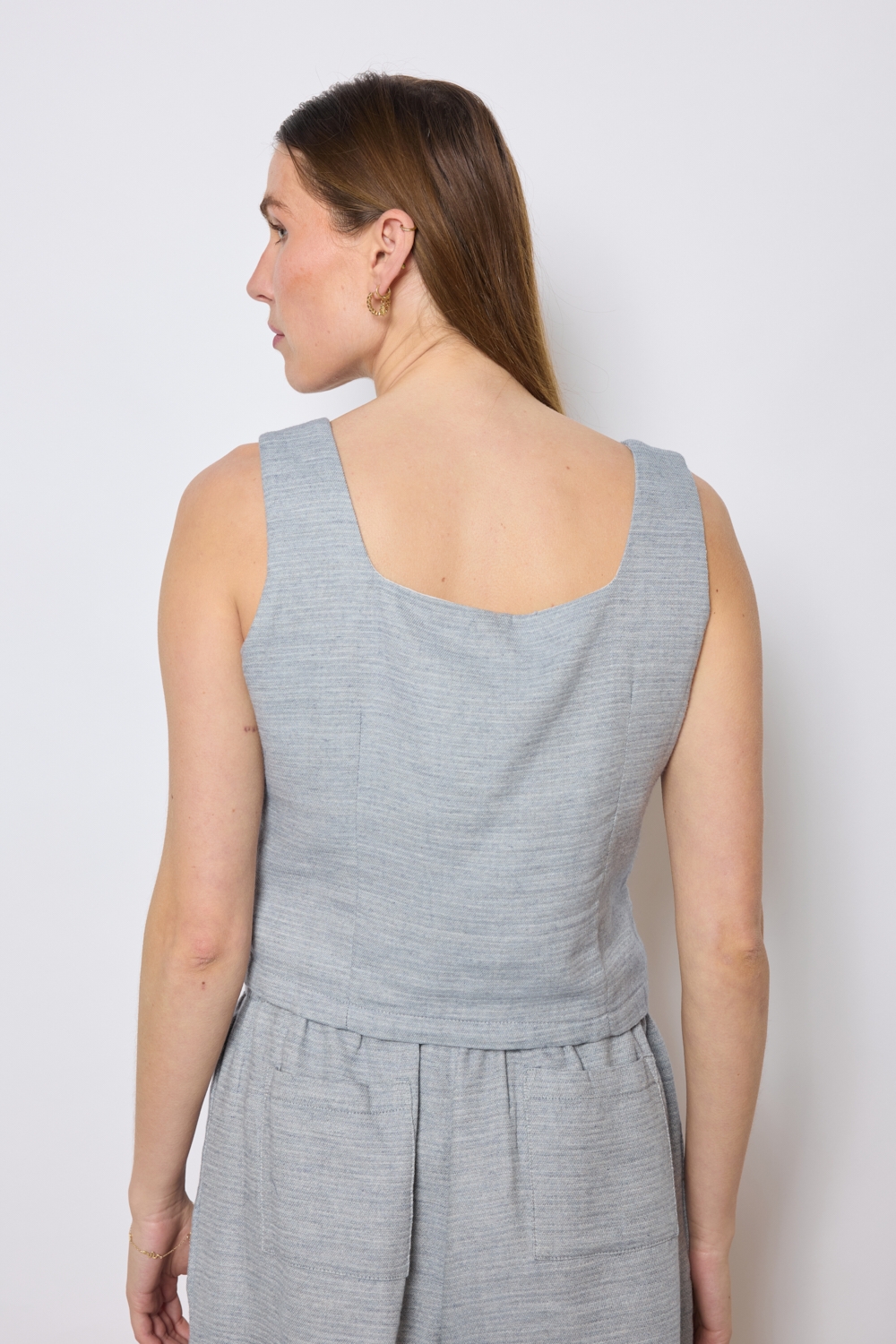 Réf. 47005A - Top ajusté avec encolure légèrement carrée et fermeture boutonnée sur le devant. Pinces discrètes pour une coupe structurée. Finition droite à la base.