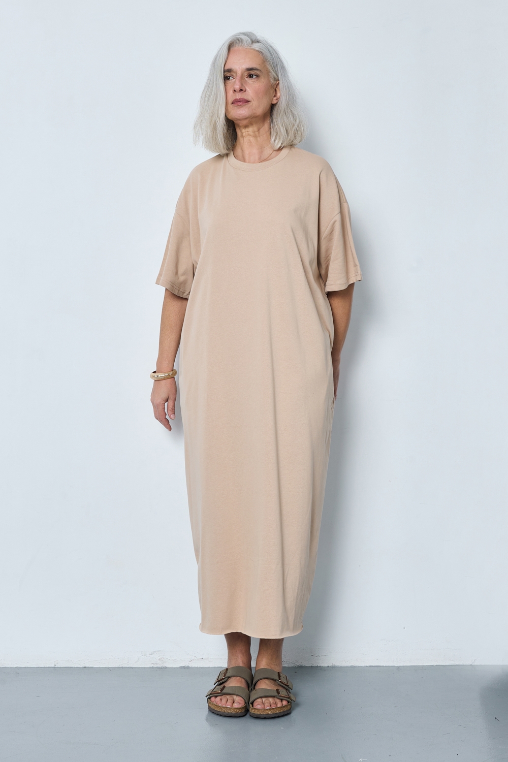 Réf. 43015A - Robe t-shirt. La robe a des manches courtes, une encolure ronde, poches sur les côtés et une coupe droite qui tombe de manière décontractée sur le corps. Sa simplicité est soulignée par l'absence de motif ou de détails superflus, ce qui en fait une pièce versatile qui pourrait être accessoirisée de diverses manières.