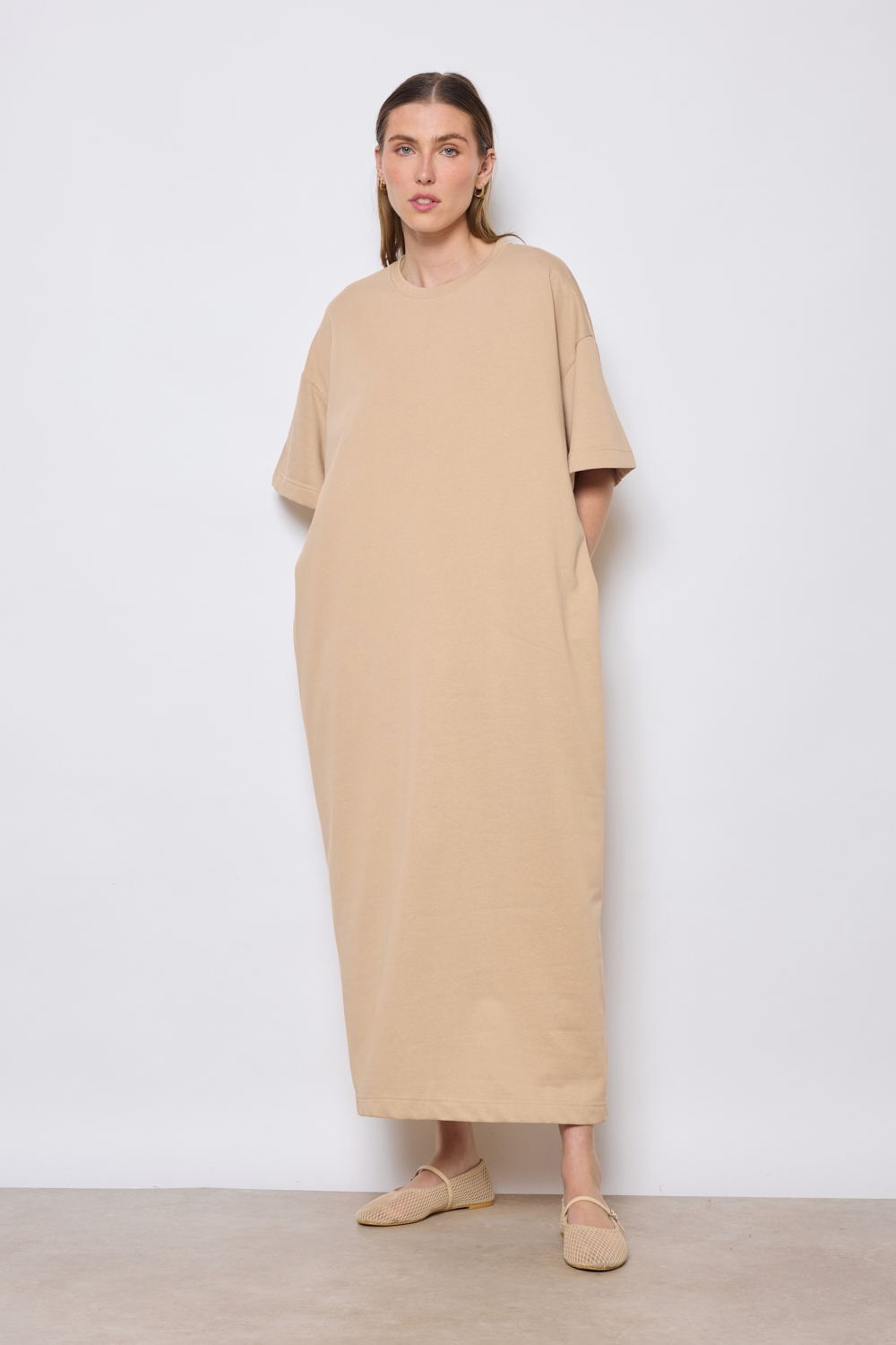 Réf. 43015A - Robe t-shirt. La robe a des manches courtes, une encolure ronde, poches sur les côtés et une coupe droite qui tombe de manière décontractée sur le corps. Sa simplicité est soulignée par l'absence de motif ou de détails superflus, ce qui en fait une pièce versatile qui pourrait être accessoirisée de diverses manières.