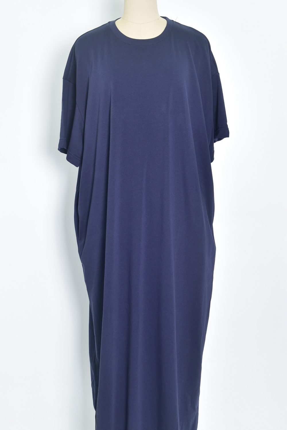 Réf. 43015B - Robe t-shirt de couleur marine. La robe a des manches courtes, une encolure ronde, poches sur les côtés et une coupe droite qui tombe de manière décontractée sur le corps. Sa simplicité est soulignée par l'absence de motif ou de détails superflus, ce qui en fait une pièce versatile qui pourrait être accessoirisée de diverses manières.